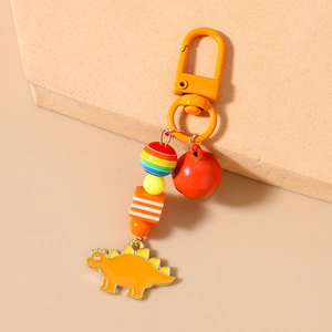 Detailed view of orange dinosaur keychain with colorful beads and small red bell