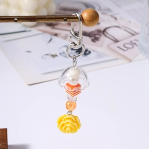 Détail du pendentif rose jaune et des perles rayées orange sur le porte-clés perlé