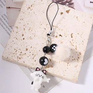 Süßer schwarz-weißer Katzenanhänger mit flauschigem Ball und Perle auf Steinuntergrund