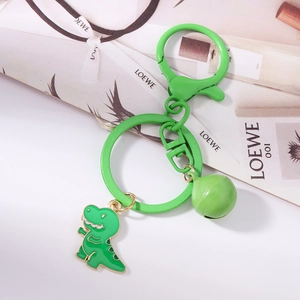 Close-up of green enamel dinosaur keychain with metal ring and matching bell charm