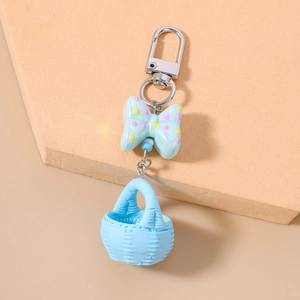 Detail of blue polka dot bow and woven basket pendant on a metallic silver keychain