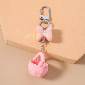 Detail view of pink macaron basket keychain with polka dot bow and silver metal clasp