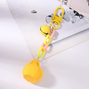 Détail du porte-clés panier tressé jaune avec chaîne en plastique colorée et cloche