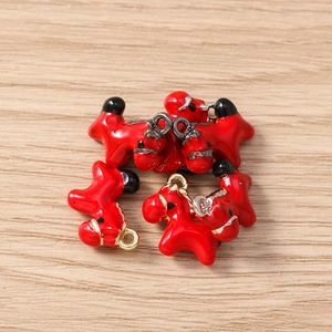 Detailed view of five red enamel puppy charms for jewelry making on wood background