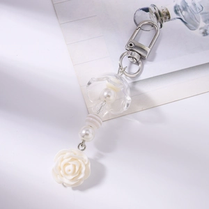 Détail du pendentif rose blanche élégant et perles nacrées sur un porte-clés argenté