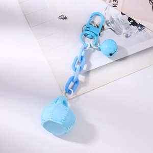 Détail d'un porte-clés bleu clair avec chaîne plastique, clochette et pendentif tressé