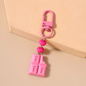 Detail of pink chocolate keychain with MILK text and bite mark on matte finish