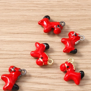 Close-up of red enamel horse pendants with gold and silver loops on wood background