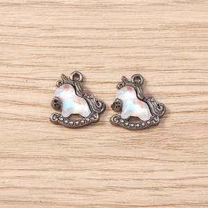 Macro detail of dark metal unicorn rocking horse pendants with iridescent resin inlay