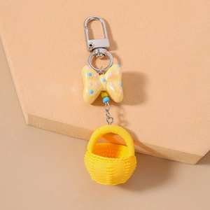 Detailed shot of yellow woven basket keychain with polka dot bow and silver metal clip