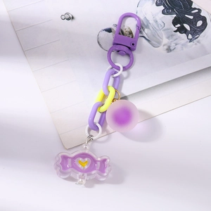 Détail de porte-clés bonbon violet avec chaîne en plastique et pendentif cœur gravé