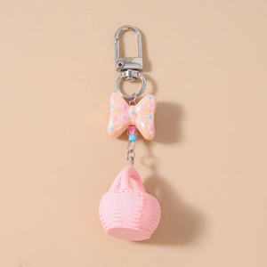 Detail of light orange polka dot bow with pink miniature basket keychain on silver hook