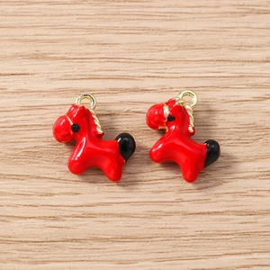 Close-up of red and black enamel horse charms with golden alloy hooks for DIY jewelry making