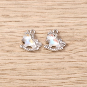 Macro detail of two silver unicorn pendants with iridescent shells for DIY jewelry making