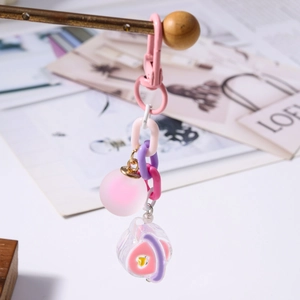 Détail d'un pendentif cœur en résine rose avec chaîne épaisse et porte-clés à perles