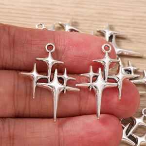 Macro view of vintage silver star pendant charms with intricate layered four-pointed details