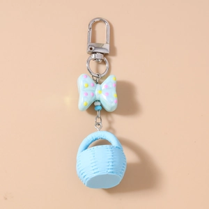Detail of light blue bow and mini woven basket charm on a metal lobster clasp keychain