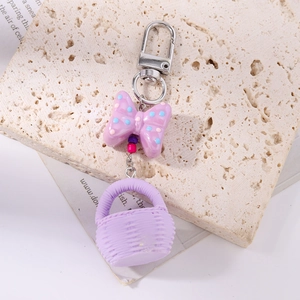 Detail of purple polka dot bow and miniature woven basket charm on a keychain