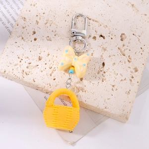 Close-up of yellow spotted bow and woven basket keychain on decorative stone