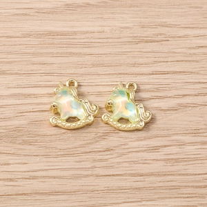 Detail of colorful unicorn rocking horse pendants with golden loops on wood background
