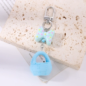 Detail of light blue polka dot bow and woven basket charm on a metal keychain