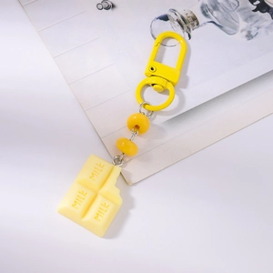 Macro shot of yellow chocolate charm keychain with MILK engraving and bead details