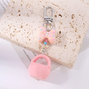 Close-up of a pink woven basket keychain with orange polka dot bow on a stone prop