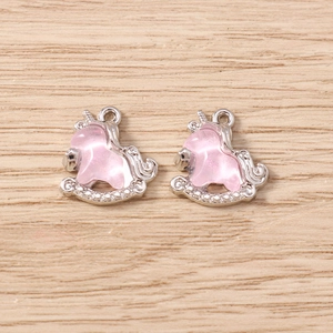 Macro detail of two silver unicorn rocking horse charms with pink glitter for DIY jewelry