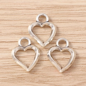 Tre ciondoli a cuore in argento vintage con asole su fondo in legno chiaro