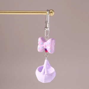Detailed view of a purple resin bow and woven basket charm keychain with silver ring