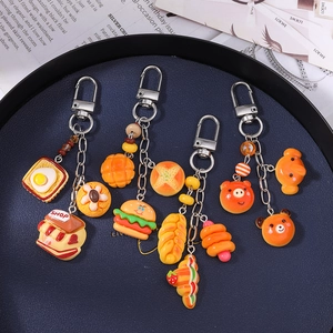 Set of four cute resin bread and bear charms with silver alloy keyrings on a blue tray