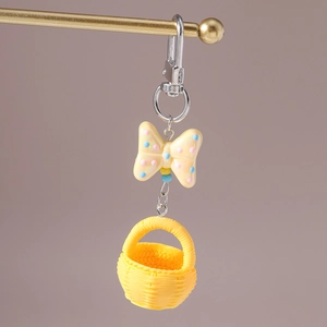 Detailed view of yellow spotted resin bow and miniature woven basket keychain charm