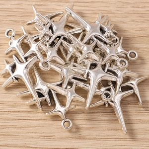 Bulk silver four-pointed star pendants for DIY jewelry making on a wooden background