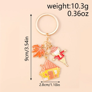 Detail of Scarecrow keychain with orange maple leaf and house charms on beige background