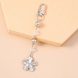 Détail du porte-clés fleur argentée avec perles métalliques et pendentif fleur en cristal
