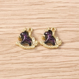 Detail of two golden rocking horse charms with purple glitter enamel for DIY jewelry making