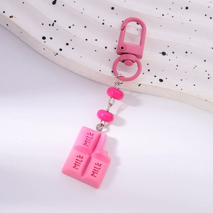 Detail of pink milk chocolate keychain with lobster clasp and beads on a wavy background