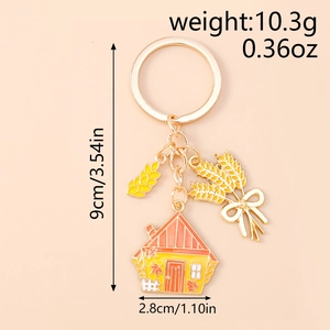 Detail view of scarecrow house keychain with maple leaf and wheat ear charms