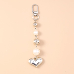 Gros plan d'un pendentif coeur argenté avec perles blanches sur un porte-clés élégant