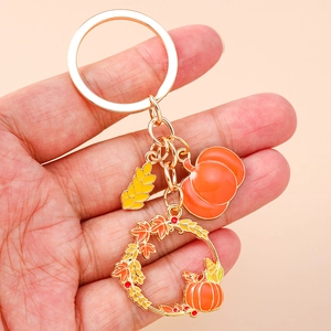 Autumn harvest keychain featuring gold enamel pumpkin and maple leaf charms for bags