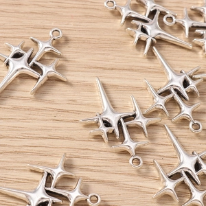 Macro shot of silver alloy star charms for DIY jewelry making on a light wood background
