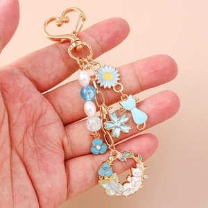 Porte-clés doré avec pivoines bleues, breloques chat et perles blanches élégantes