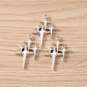 Three vintage silver four-pointed star charms for DIY jewelry making on wooden background