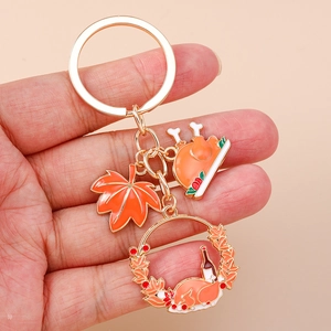 Detailed close-up of Thanksgiving turkey and maple leaf charms on a golden metal keychain