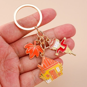 Scarecrow and harvest house keychain with orange maple leaf charm on golden ring