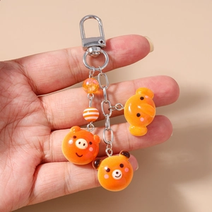 Detail of cute orange bear and pig resin pendants on a silver metal keychain