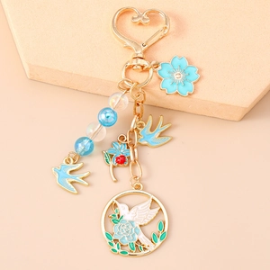 Détail du pendentif hirondelle bleue et cerisier sur porte-clés doré en forme de cœur