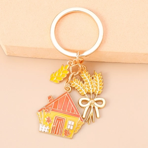 Detail of metal keychain with autumn house charm and golden wheat spike pendant