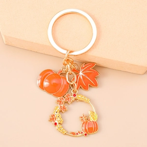 Detail of autumn-themed keychain featuring enamel pumpkin, maple leaf and floral wreath charm