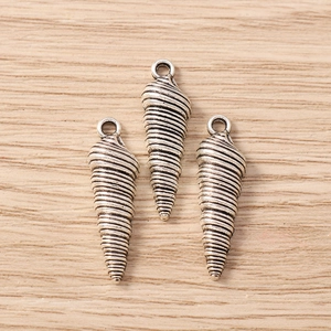 Dettaglio macro di tre ciondoli a conchiglia d'argento con trama vintage su legno
